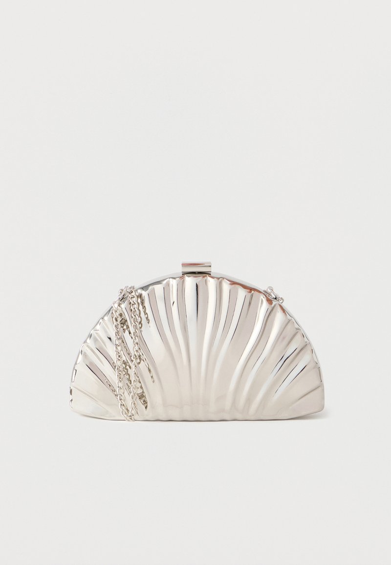 Pochette argentée métallique en forme de coquillage, avec une chaîne en argent drapée sur le côté.