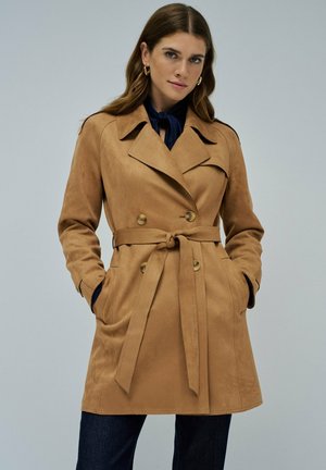 Manteau trench double boutonnage en tan, fabriqué dans un matériau doux semblable au daim, avec une taille ceinturée, de grands revers et deux poches latérales.