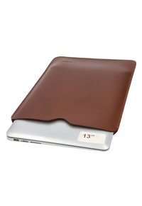 Silver 13-inch laptop partially inside a brown leather sleeve with a curved opening at the top edge.
