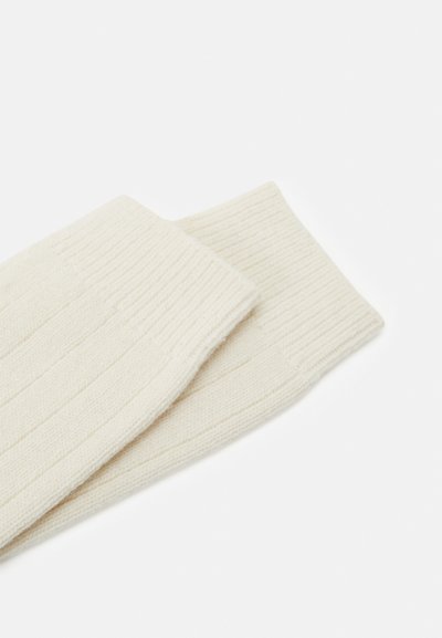 Ribbede off-white benvarmere lavet af blødt stof, der har en tætsiddende pasform og en glat tekstur, ideelle til varme og komfort.