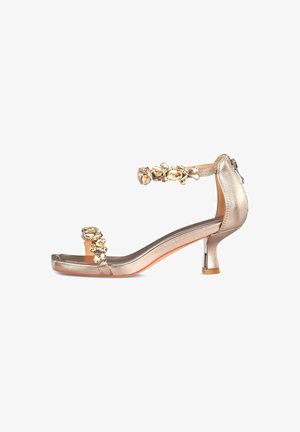 Gold metallic high-heeled sandal with a square toe, embellished ankle strap, and a decorative cluster of clear and gold stones.