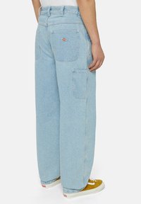 Pantalones cargo de denim azul claro con un corte relajado, que cuentan con grandes bolsillos laterales y un pequeño parche con logo en la parte posterior.