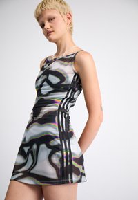 Robe mini sans manches à motif noir et blanc avec un éclat irisé, présentant trois rayures verticales noires sur les côtés et une coupe ajustée.