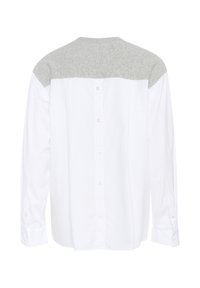 Camicia bianca con un giogo in maglia grigia, maniche lunghe e chiusura con bottoni sul retro. Presenta una texture liscia e un design del colletto classico.