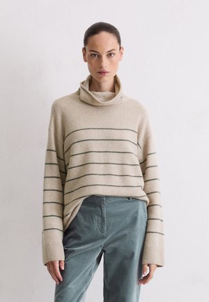 Maglione beige a righe con collo alto a cowl, caratterizzato da strisce orizzontali verdi. Tessuto morbido, maniche ampie, abbinato a pantaloni turchesi.
