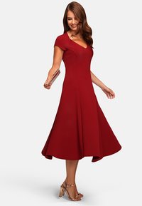 Red, fitted dress with cap sleeves and a flared skirt. Made of smooth fabric, it features a V-neckline and a knee-length hem.