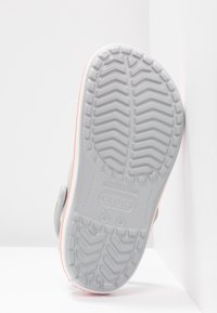 Semelle d'une chaussure Crocs gris clair avec un motif de la bande de roulement détaillé, des marquages de taille et des logos de marque visibles sur fond blanc.