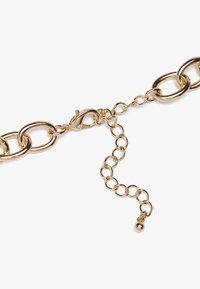 Goldene Kette mit großen, verwobenen Gliedern und einem Karabinerhaken. Enthält eine verstellbare Verlängerungskette mit einem kleinen sphärischen Enddetail.