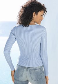 Himmelblau gerippter Langarmpullover mit taillierter Silhouette, Rundhalsausschnitt und strukturiertem Material, kombiniert mit mittelblauen Jeans.