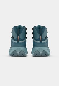 Pantofi de drumeție teal cu un design înalt la gleznă, țesătură texturată și structură suportivă. Prezintă găuri întărite pentru șireturi și o talpă cu model.