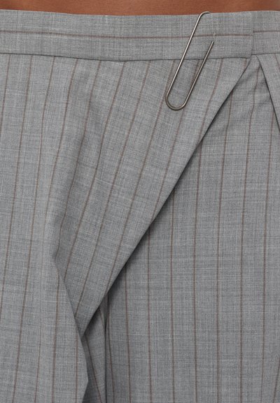 Gray pinstripe fabric with a subtle texture. The fabric features vertical stripes in darker gray and brown. A paperclip accent is visible.