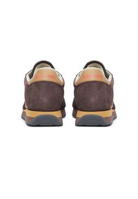 Sneaker in suede marrone con colletto crema e logo "Saucony" rosa. Presentano una suola in gomma nera testurizzata e accenti color sabbia sulla soletta.