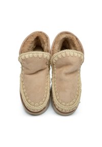 Zapatillas de ante beige con forro de forro polar, con ribete trenzado y forma redondeada. Textura suave y materiales blandos para mayor comodidad.