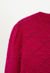 Pull rouge en tricot avec motif losange et détails en boules en relief, avec un col rond côtelé et un tissu texturé.