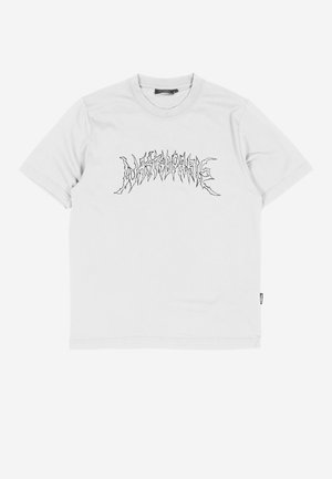 T-shirt blanc à manches courtes avec un texte stylisé noir en forme de zigzag sur la poitrine, sur un fond uni.