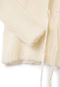 Cremfarbener, strukturiert gestrickter Pullover mit Kapuze, ausgestattet mit einem Kordelzug, gerippten Bündchen und einem leicht ausgefransten Saum.