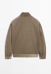 Giacca in corduroy marrone con collo alto, texture a coste visibile, maniche lunghe e orlo dritto. Senza chiusure né decorazioni.