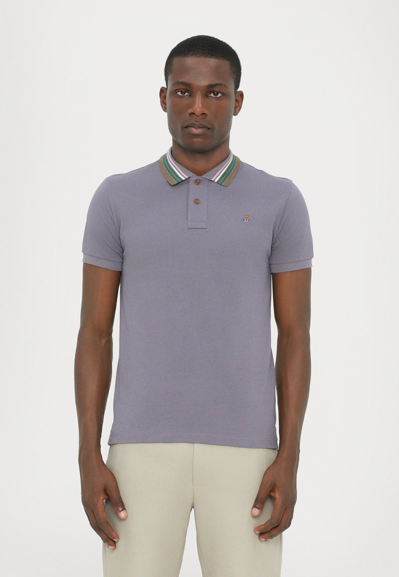 Polo en lavanda con un cuello a rayas. Mangas cortas, tapeta de dos botones, logo bordado en el pecho, textura de algodón suave.