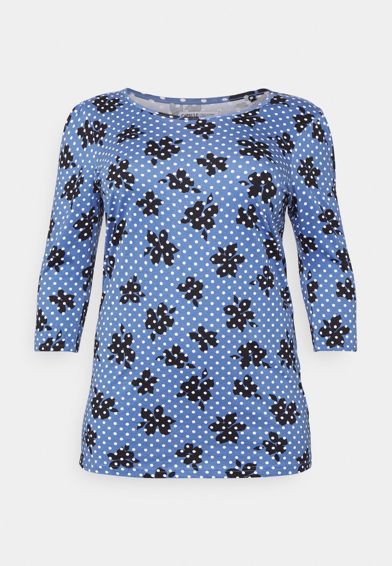 Camisola azul com mangas de três quartos, apresenta padrões florais pretos sobre um fundo de bolinhas, feita de material leve e suave.