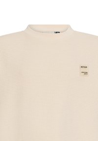 Schweißshirt aus Waffelstruktur mit geripptem Rundhalsausschnitt und einem kleinen schwarz-weißen Etikett mit der Aufschrift "RETOUR" auf der Vorderseite.