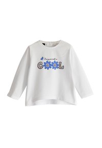 Chemise blanche à manches longues avec un col rond, ornée d'un texte graphique floral bleu et noir disant "Être soi-même est COOL". Matériau doux.