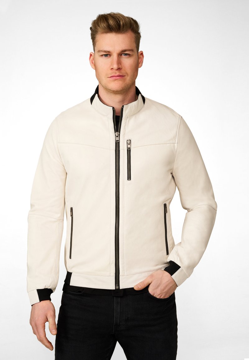 Veste bomber en cuir blanc avec fermeture éclair à l'avant, accents noirs, deux poches latérales et poignets et ourlet côtelés. Texture lisse, design ajusté.
