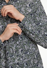 Langermige shirt met een bloemmotief in groen, grijs en marineblauw. Bevat een knoopmanchet en een verborgen knoopsluiting. Glad stoffen textuur.
