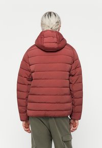 Rote Pufferjacke mit horizontal gestepptem Design und einer verstellbaren Kapuze. Verfügt über eine elegante Textur und einen leicht lockeren Schnitt, ideal zum Schichten.