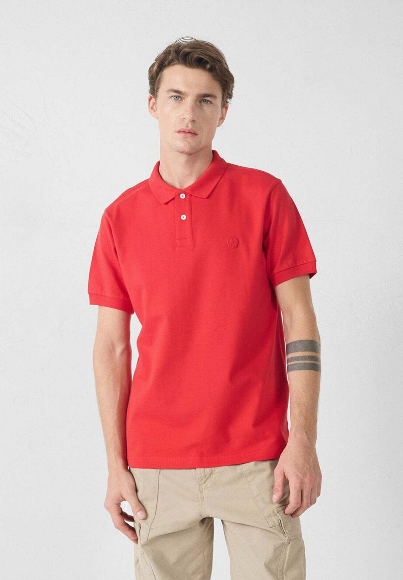 Rode poloshirt gemaakt van glad katoen, met een klassieke kraag, twee knopen in de sluiting en een klein logo op de borst. Effen ontwerp, korte mouwen.