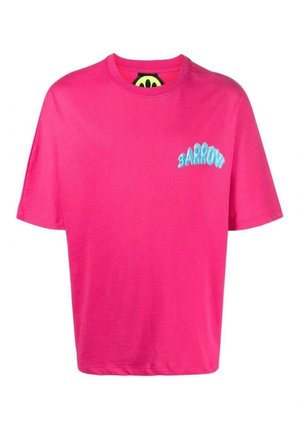 Homme portant un T-shirt oversize rose vif avec le texte bleu « BARRIUM » sur la poitrine gauche, associé à un pantalon noir, sur un fond clair uni.