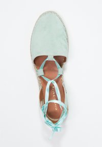 Espadrille de ante verde menta con punta redonda, suela de yute trenzado y cintas de satén en el tobillo. Textura suave con plantilla de color marrón claro.