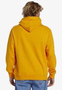 Yellow hoodie made of soft fabric, featuring a kangaroo pocket and adjustable hood. Finished with ribbed cuffs and hem.