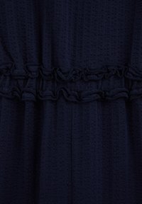 Tumši tumši zils fakturēts audums ar horizontālu kroku šuvi pāri centram.