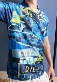 Pánská polokošile s krátkým rukávem v modré barvě, zdobená výraznými grafickými potisky, texturovanými vzory a textovými prvky v žlutých a bílých akcentu.