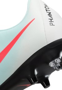 Heledad sinine jalgpallijalats punase Nike swooshiga, tekstuuriga ülemine materjal, must väline tallaosa ja läbipaistvad nibud haardeks.
