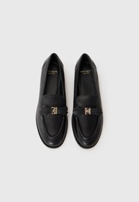 Black leather loafers with a rounded toe, featuring a decorative bow and metallic hardware on the front. Smooth texture, flat sole.