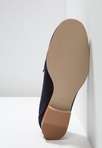 Scarpa in suede blu navy con suola in gomma e dettagli testurizzati sulla parte inferiore. Taglia "37" stampata vicino al tallone.
