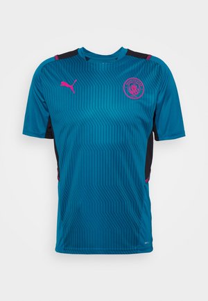 Maillot de football bleu à manches courtes de Manchester City avec des rayures foncées, logo Puma rose et blason du club à l'avant sur fond blanc.