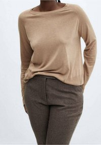 Beige lange mouwen sweater met een brede halslijn, zachte textuur, gecombineerd met bruine gemêleerde broek. Eenvoudig, aansluitend ontwerp zonder versieringen.