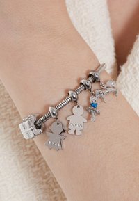 Zilveren bedelarmband met metalen figuren, een met kristallen versierde ballerina, en een paard, met gestructureerde kralen en een veilige sluiting.