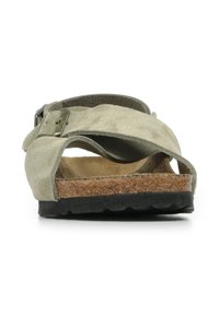 Sandalo slide in suede verde tenue con fasce incrociate e soletta in sughero. Suola in gomma nera con grip testurizzato per stabilità.