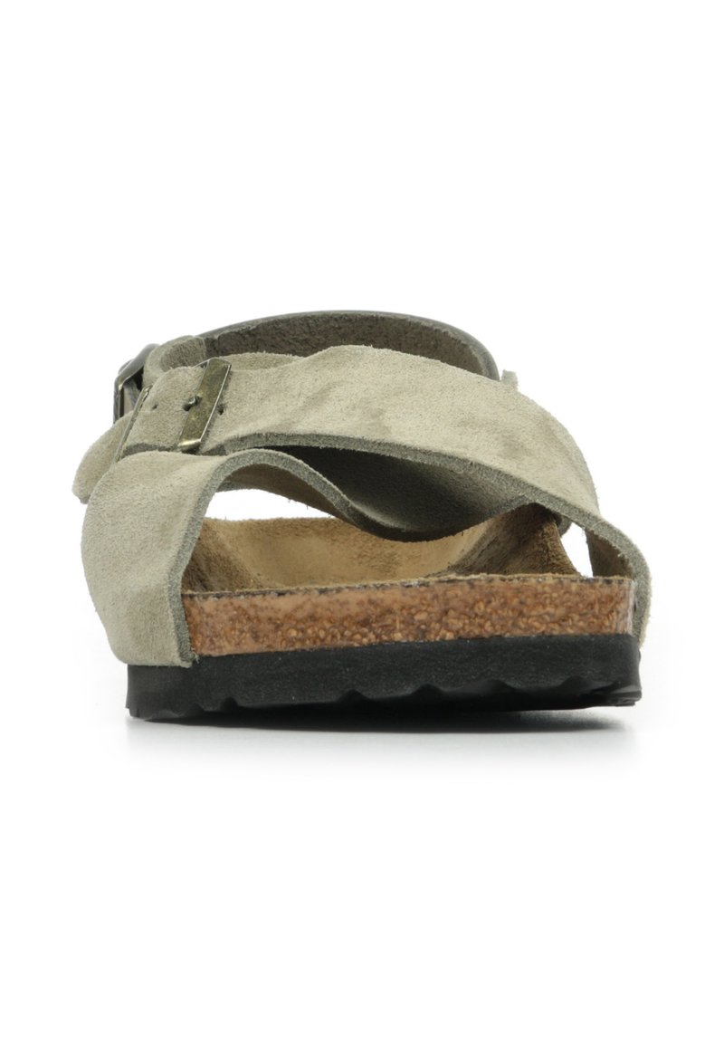 Suede slide sandal in muted green with crisscross straps and a cork footbed. Black rubber sole with textured grip for stability.