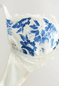 Soutien-gorge avec armatures à motif floral bleu sur un tissu blanc. Dentelle le long du bord supérieur, texture douce, matériau satin de qualité supérieure et couture délicate.