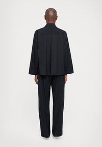 Marinblå randig outfit med en lös, långärmad skjorta och matchande vida byxor, tillverkad av ett slätt tyg.