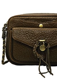 Sac croisé en cuir texturé marron avec poche à rabat à l'avant, bandoulière en chaîne dorée et charm Mila Louise Paris rond en or avec des glands en cuir.