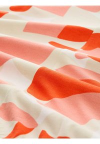 Tissu abstrait présentant de grandes formes superposées dans des couleurs corail, pêche et crème. Tissu doux avec une texture lisse.