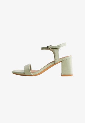 Lichtgroene sandaal met open teen, blokhak, enkelriem en gespsluiting, zijaanzicht op witte achtergrond.
