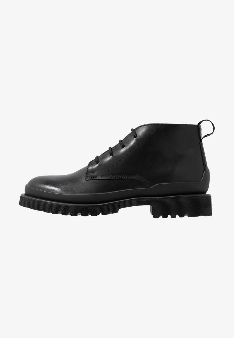 Bottine noire en cuir avec laçage sur le devant, semelle en caoutchouc robuste et languette à l'arrière, présentée de profil sur fond blanc.