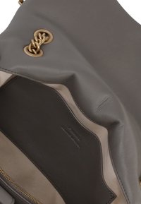 Borsa in pelle grigia con dettagli in catena dorata, dotata di interno in tessuto beige e tasca in pelle scura con logo impressa.