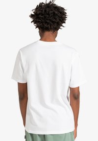 Hvid kortærmet t-shirt lavet af bomuld, med klassisk rund hals og afslappet pasform, set fra ryggen. Glat tekstur, ingen mønstre.